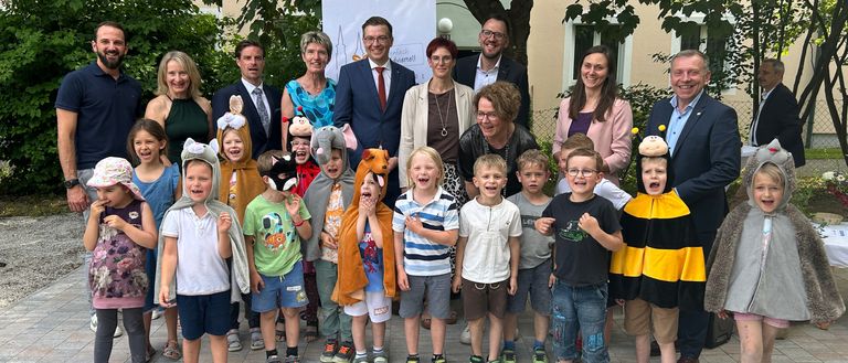 Eine Gruppe von Erwachsenen und Kindern in Kostümen posiert für ein Foto im Garten.