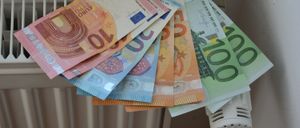 Ein Stapel von Euro-Banknoten in Nennwerten von 5, 10, 20, 50 und 100 Euro, auf einem Heizkörper platziert.