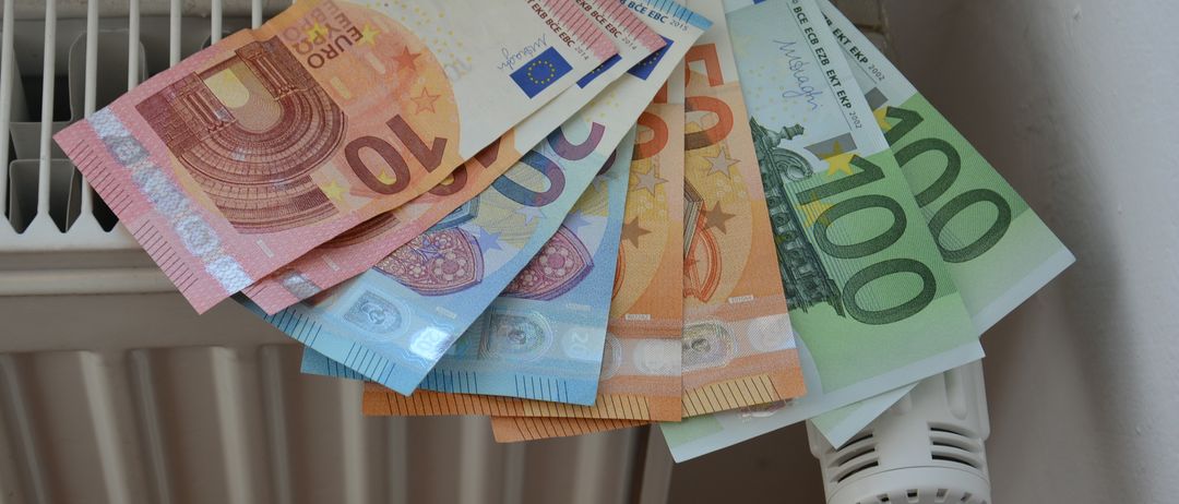 Ein Stapel von Euro-Banknoten in Nennwerten von 5, 10, 20, 50 und 100 Euro, auf einem Heizkörper platziert.