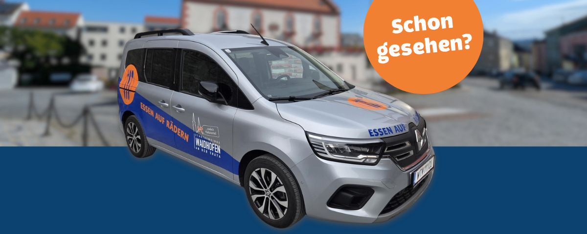 Ein silberner Renault mit Essen auf Radern Text an der Seite und der vorderen Stoßstange. Ein orangefarbener Kreis mit dem Text Schon gesehen? oben rechts.