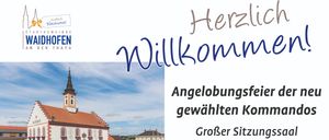 A blue and white poster reads 'Willkommen' in blue cursive font with a picture of a town with a church tower and a blue sky. Below the picture is the website address www.waidhhofen-thaya.at.