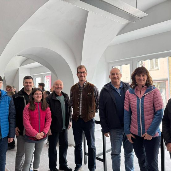 Eine Gruppe von Menschen steht und posiert für ein Foto in einem Raum mit weißen gewölbten Decken.