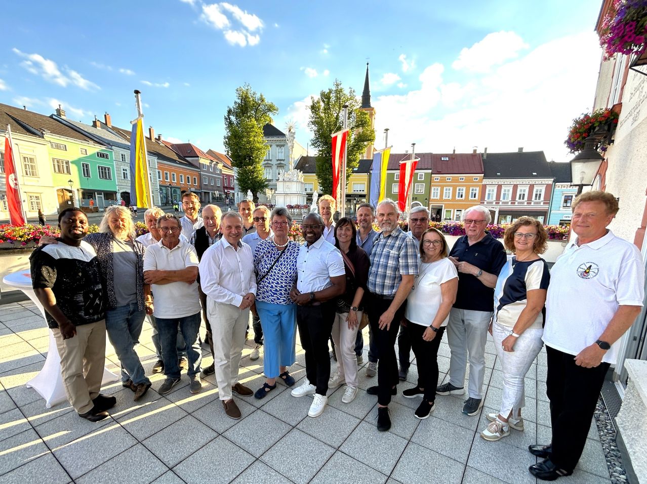 Gruppe von Menschen steht vor bunten Häusern in einem österreichischen Ort.