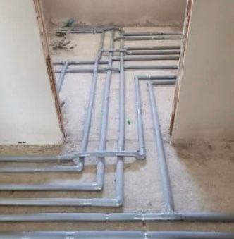 Innenbereich einer Baustelle mit grauen Rohren auf dem Boden.