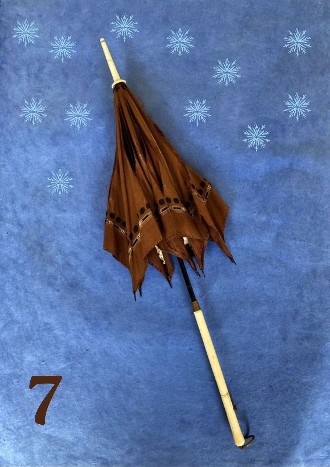 Ein brauner Vintage-Sonnenschirm mit dekorativen Punkten auf blauem Hintergrund mit Schneeflocken, Nummer 7 in der linken Ecke.