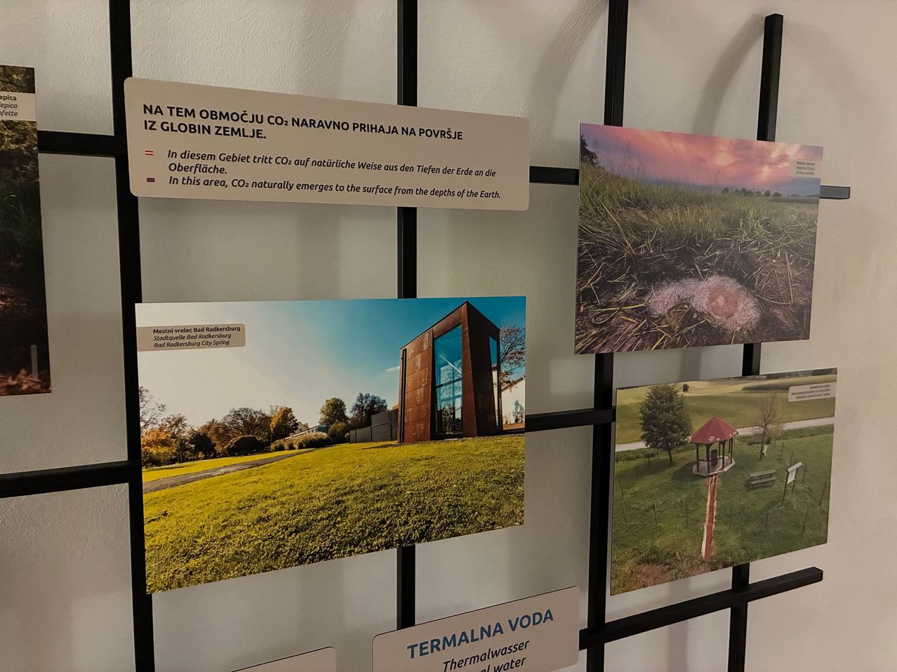 A wall with multiple images and text. One image shows a grassy field with a house, while another shows a landscape with a birdhouse and trees. The text explains how CO2 naturally emerges from the Earth's depths.