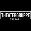 Auf einem schwarzen Hintergrund steht weißer Text 'Theatergruppe Fussach', wobei 'Theatergruppe' oben und 'Fussach' unten steht. Der Text befindet sich in einem weißen Rechteckrahmen.