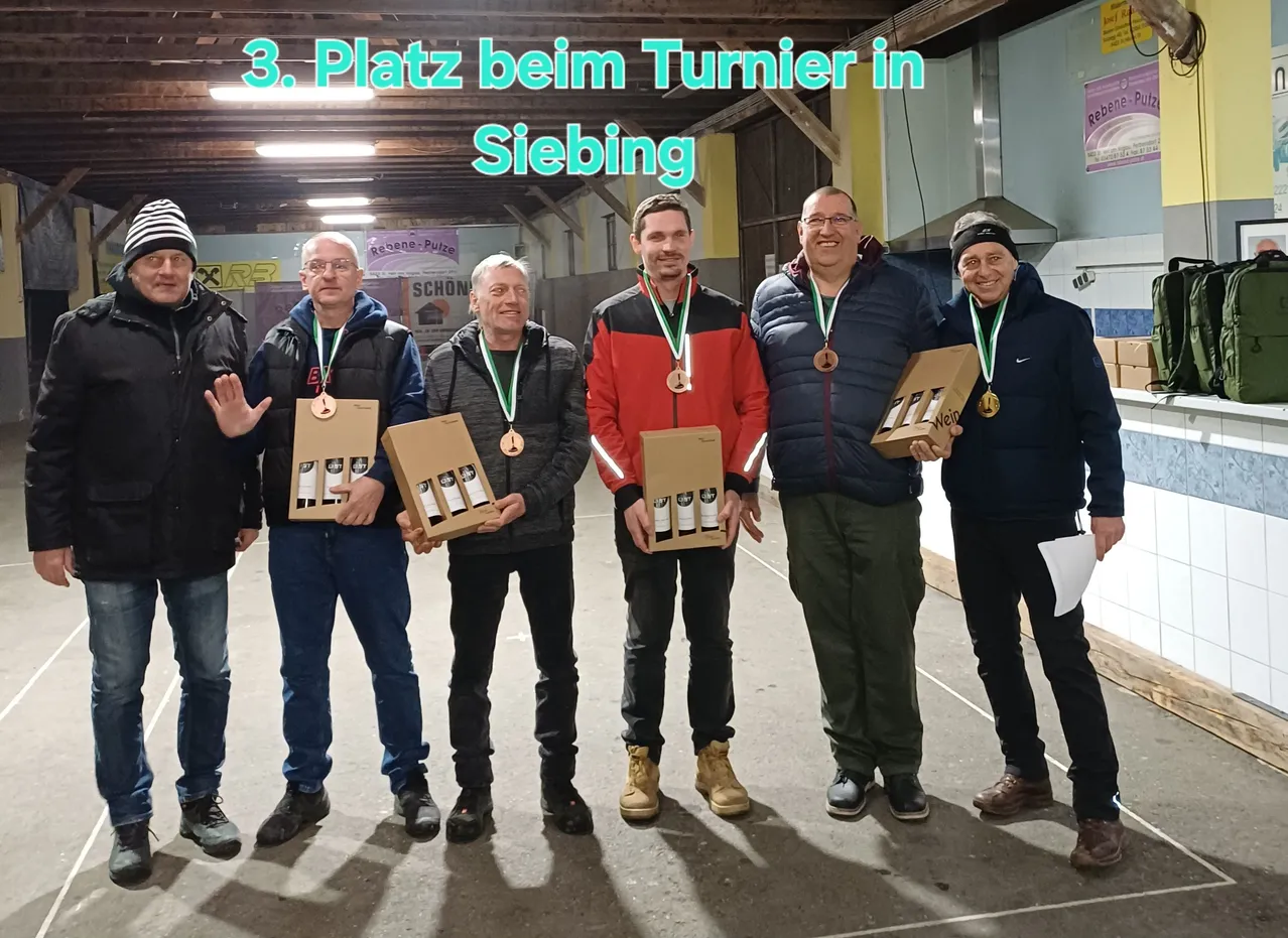 Fünf Männer stehen zusammen und halten Weinkartons in der Hand, tragen Medaillen. Sie befinden sich in einem Innenbereich mit einem Banner darüber, das '3. Platz beim Turnier in Siebing' steht.
