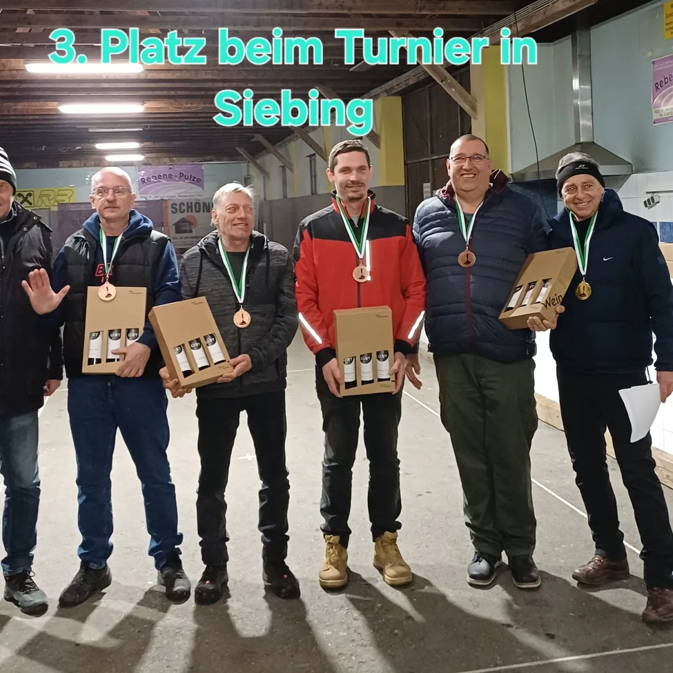 Fünf Männer stehen zusammen und halten Weinkartons in der Hand, tragen Medaillen. Sie befinden sich in einem Innenbereich mit einem Banner darüber, das '3. Platz beim Turnier in Siebing' steht.