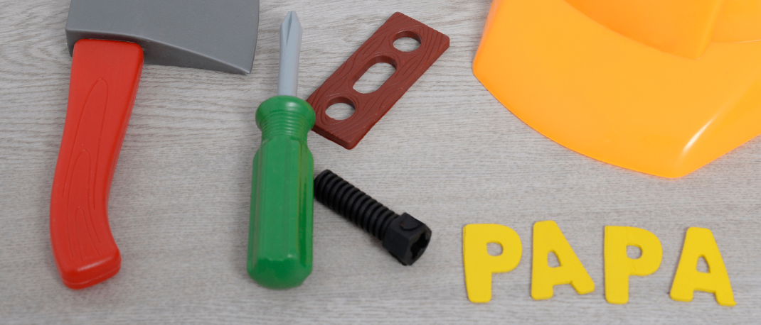 Bauspielzeuge auf einer Holzoberfläche, einschließlich eines gelben Helms, eines rotgriffigen Axt, eines grüngriffigen Schraubendrehers, eines braunen Ausschnitts und eines schwarzen Stücks. Das Wort 'PAPA' ist in Gelb geschrieben. Ein rundes Logo mit 'EKIZ' und 'ELTERN-KIND-ZENTRUM GLEISDORE' ist vorhanden.