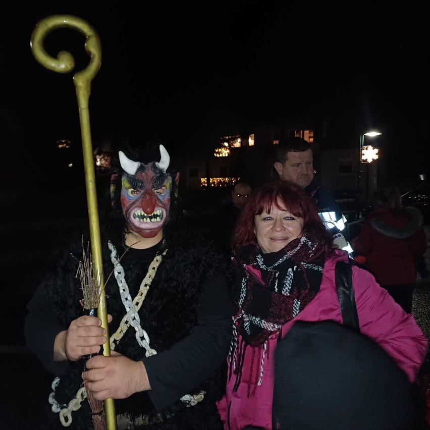 Eine Person mit einer hörnertragenden Maske hält einen Stab in einer nächtlichen Umgebung mit anderen um sie herum.