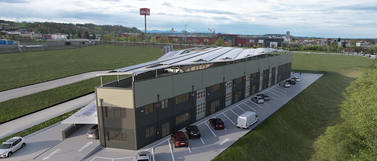 Luftaufnahme eines modernen Gebäudes mit Solarmodulen, geparkten Autos davor und einem Schild mit 'Kika'.