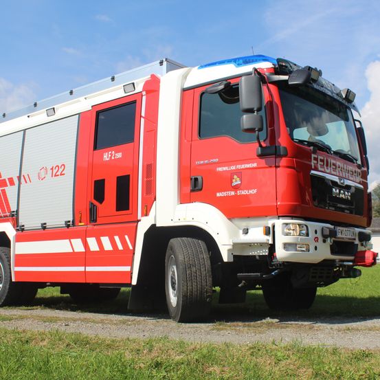 Ein roter und weißer Feuerwehrwagen mit der Nummer 122 auf der Seite ist auf einem Schotterweg unter einem blauen Himmel geparkt.