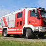 Ein roter Feuerwehrwagen mit der Aufschrift HLF 2500 und 122 ist auf einem Kiesweg geparkt. Der Wagen hat ein blaues und weißes Dach, einen roten Körper und weiße Streifen.