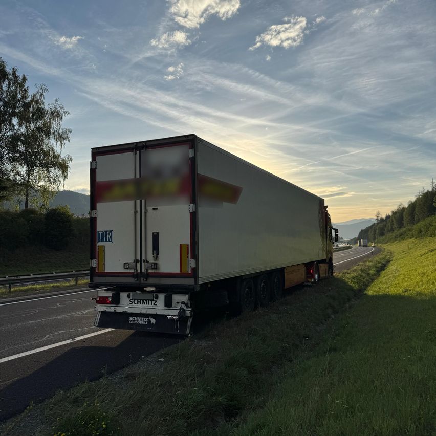 Ein großer weißer Lkw mit roten und gelben Markierungen steht am Straßenrand.