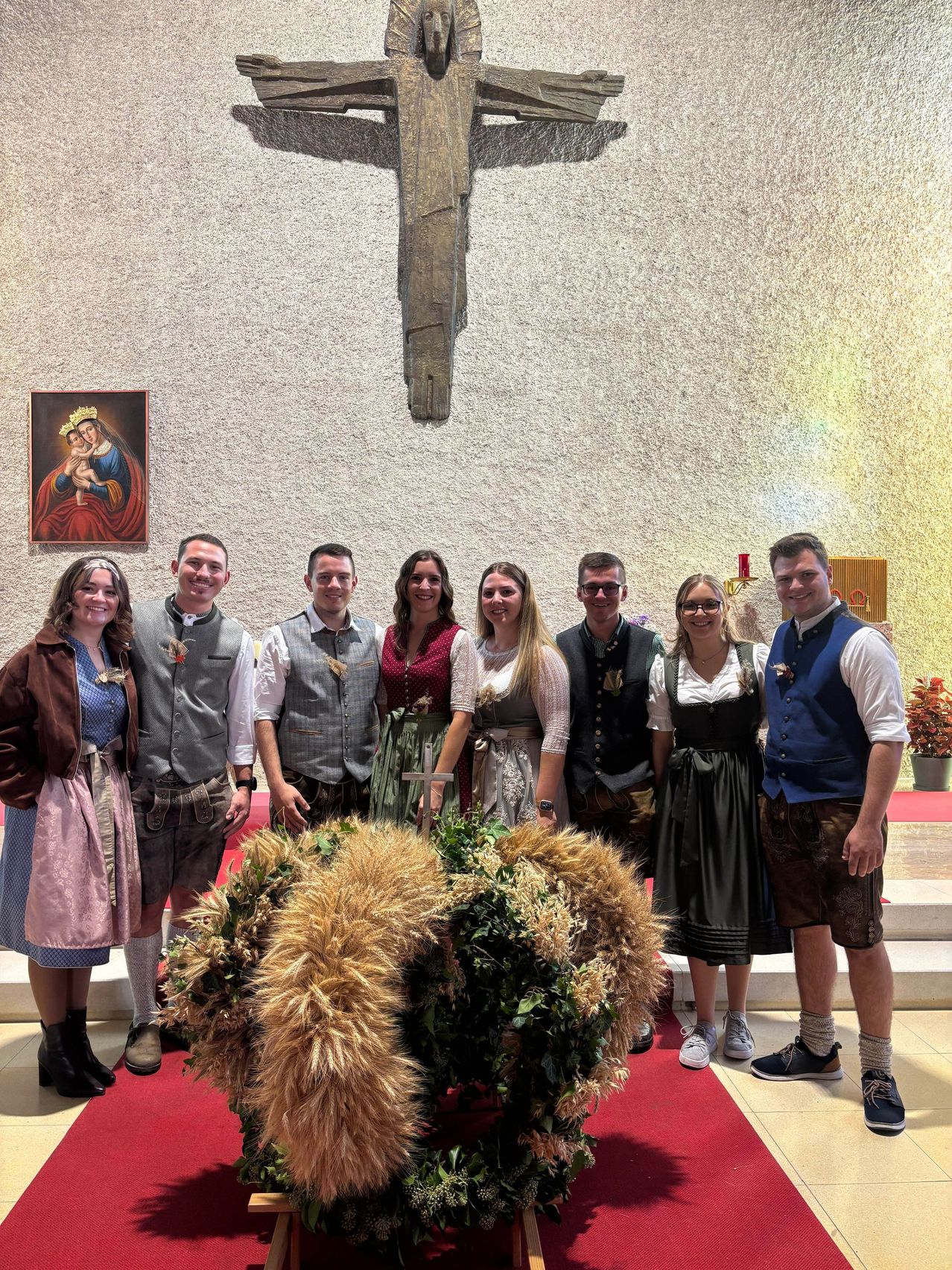 Eine Gruppe von Menschen in traditioneller bayerischer Kleidung posiert für ein Foto vor einem Kirchenaltar.
