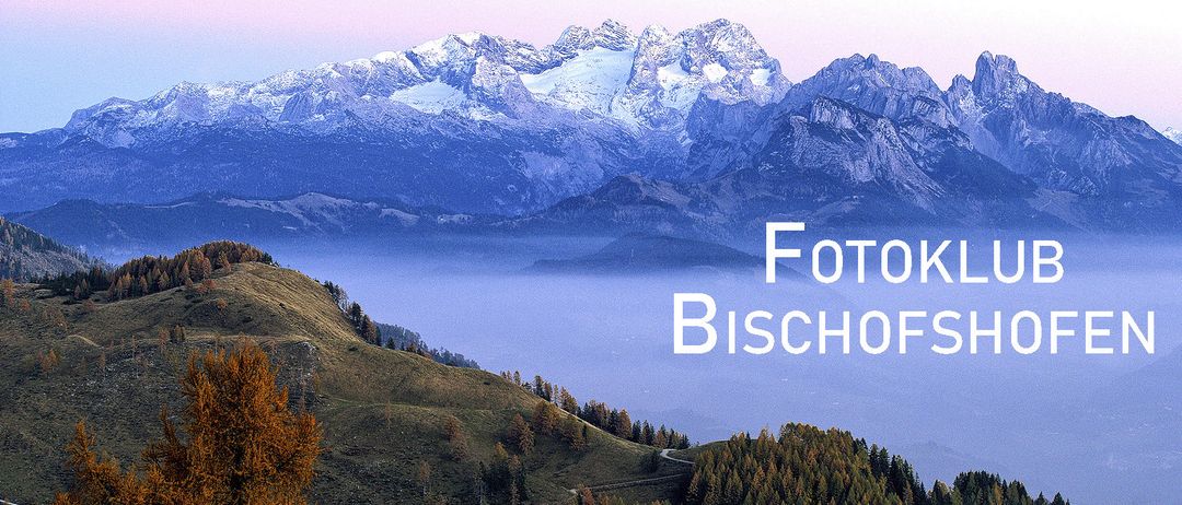 Eine Landschaftsaufnahme mit Bergen, Nebel und Bäumen, mit Textüberlagerung 'Fotokl Bischofs'.