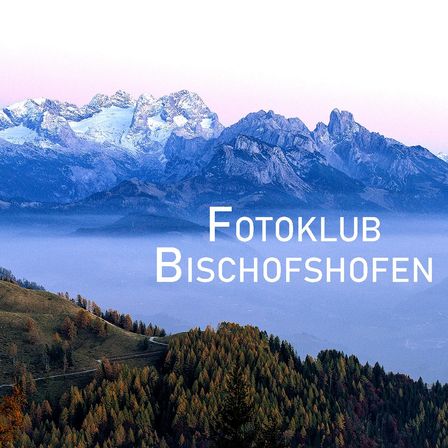 Eine Bergkette mit schneebedeckten Gipfeln und einem nebligen Tal, beschriftet mit 'Fotokl Bischofsh', umgeben von einem üppigen Wald mit Herbstlaub.
