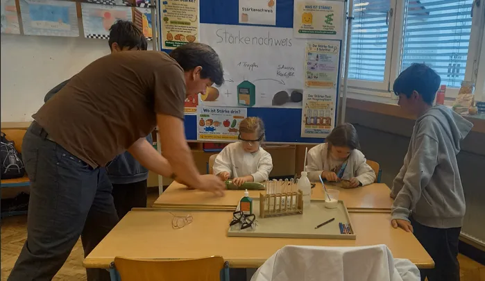 Ein Mann demonstriert ein wissenschaftliches Experiment für eine Gruppe von Kindern in einem Klassenzimmer.