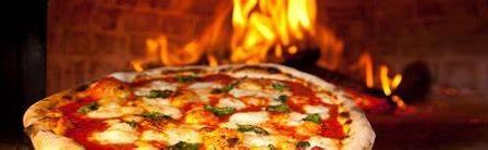 Eine Pizza mit geschmolzenem Käse, Tomatensoße und Kräutern wird in einem Holzofen gebacken. Die hellen Flammen des Ofens beleuchten die Pizza.
