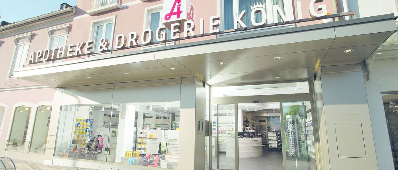 Die Fassade einer Drogerie namens A&Drogerie Kon, mit einem Schild über dem Eingang, das Regale mit Produkten im Inneren zeigt.