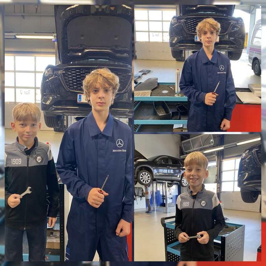 Drei junge Jungen in einer Garage, zwei halten Werkzeuge, einer in blauer Uniform, ein Auto im Hintergrund.