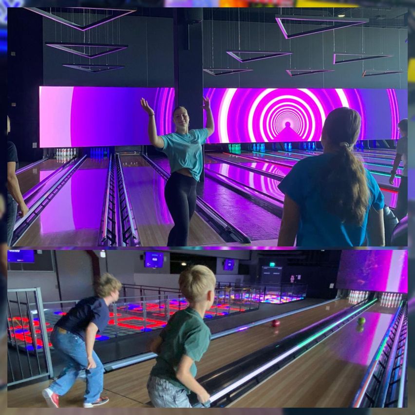 Eine Frau bowlt in einer Bowlingbahn mit lila Lichtern.