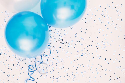 Ein Cluster aus blauen Luftballons mit blauen Bändern und Konfetti auf einem weißen Hintergrund.