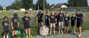 Eine Gruppe junger Jungen und Männer in passenden Nike-Shirts posiert für ein Foto vor einem Zaun mit einem Baum.