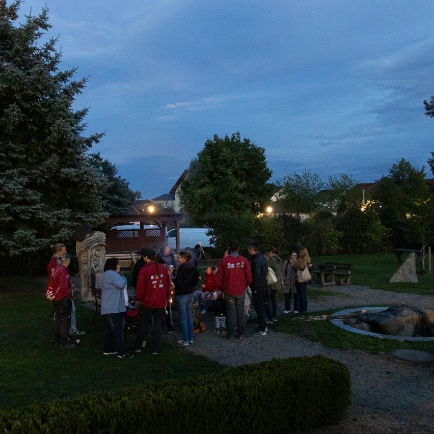 Eine Gruppe von Menschen versammelt sich nachts in einem Park um ein Feuer herum.