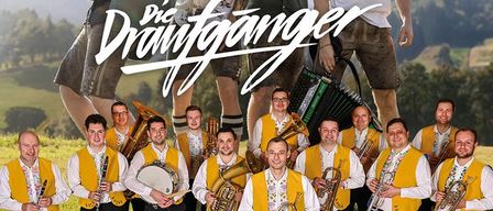 Eine Gruppe von Musikern posiert auf einer Wiese, mit einem Berg im Hintergrund. Die Gruppe lächelt und scheint für ein Foto zu posieren. Es sind mehrere Instrumente zu sehen, darunter Trompeten, ein Posaune und eine Trommel. Das Bild enthält den Text 'Die Draufganger' und 'VLADO KUMPAN und seine Musikanten'.