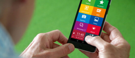 Eine Person hält ein Smartphone mit Symbolen wie Anruf, Adressbuch, Kamera, WhatsApp, Fotos und Benachrichtigungen. Der Bildschirm zeigt die Zeit 11:45 und das Datum 01.27.18.