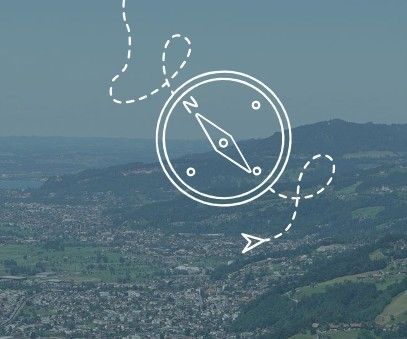 Eine Luftaufnahme einer Stadt, umgeben von Hügeln und Bergen, mit einer Kompassnadel und einem Richtungspfeil, der auf die Stadt zeigt.