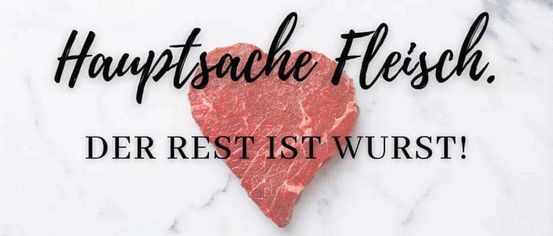Ein rotes Stück Fleisch in Herzform mit dem Text Hauptsache Fleisch und Der Rest ist Wurst auf weißem Marmorhintergrund.