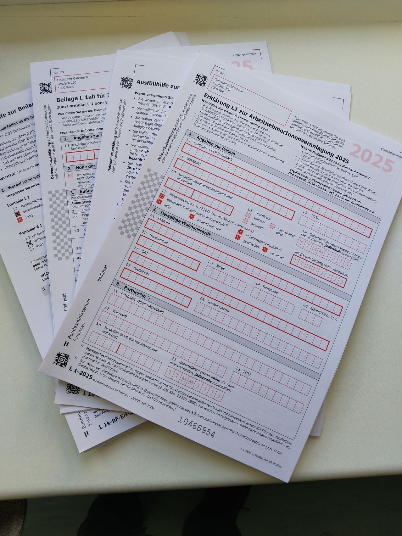 A stack of papers with multiple forms including 'Ausfullung zur', 'Erklärung L1 zur Arbeitsnehmererven', and 'Formular L1' are visible. They appear to be employment forms with sections for personal information and declarations. The forms are filled out with red and black ink.