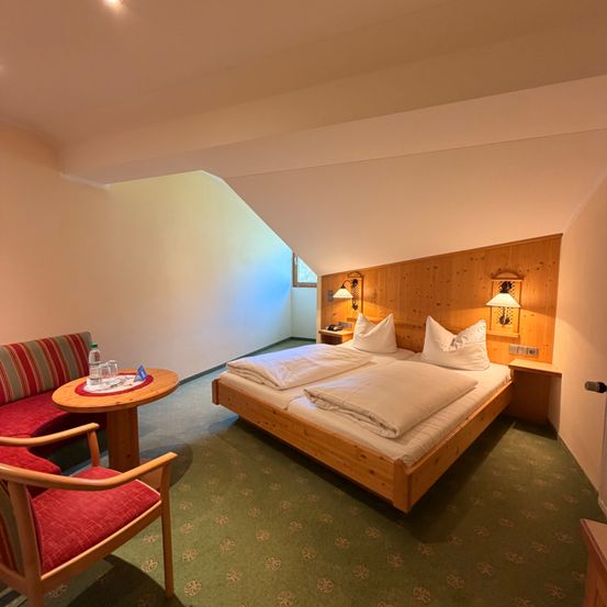 Ein Schlafzimmer mit Holzmöbeln, einem Doppelbett und einem kleinen Tisch mit Flaschen und einem Untersetzer.
