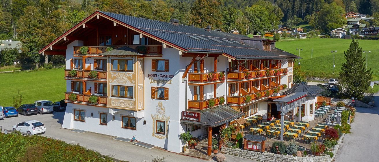 Ein Luftbild eines Hotels mit Restaurant und Terrasse. Das Hotel befindet sich in einer Bergregion, umgeben von üppiger Grünfläche und Bäumen.