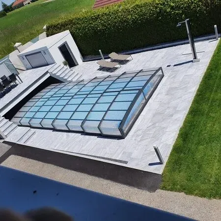 Aerial view of a modern house with a covered swimming pool and lounge chairs on the patio.