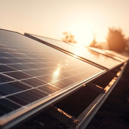 Nahaufnahme von Solarmodulen, die Sonnenlicht an einem sonnigen Tag reflektieren. Bäume und Berge sind im Hintergrund zu sehen.