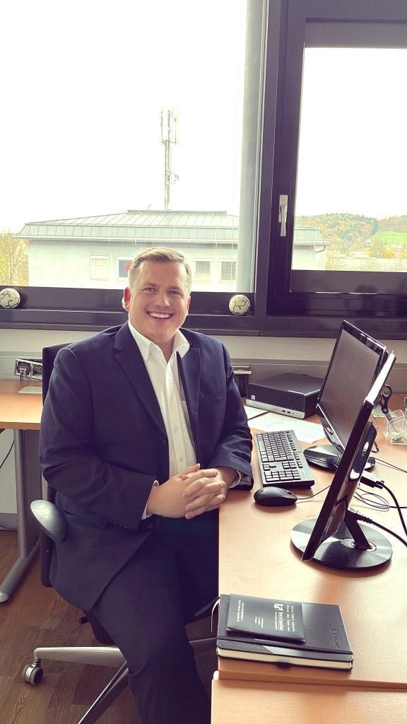 Bild enthält, Blazer, Coat, Jacket, Table, Desk, Executive, Person, Computer Keyboard, Formal Wear, Suit