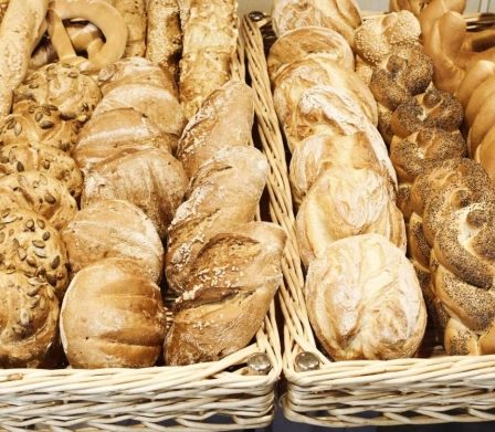 Zwei Körbe mit verschiedenen Brotsorten, einschließlich Laibe, Brezeln und geflochtene Brote, werden in einer Bäckerei ausgestellt.