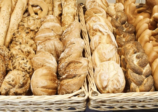 Zwei Körbe mit verschiedenen Brotsorten, einschließlich Laibe, Brezeln und geflochtene Brote, werden in einer Bäckerei ausgestellt.