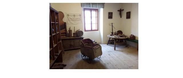 Eine Ankündigung für das Karschundler Heimatmuseum, das am Sonntag, 4. Mai 2025, von 9:00 bis 12:00 Uhr geöffnet hat. Der Innenraum des Museums ist zu sehen, mit Holzmöbeln, einem Fenster und einem Kreuz an der Wand. Das Museum kann auch außerhalb der Öffnungszeiten nach Vereinbarung besucht werden.