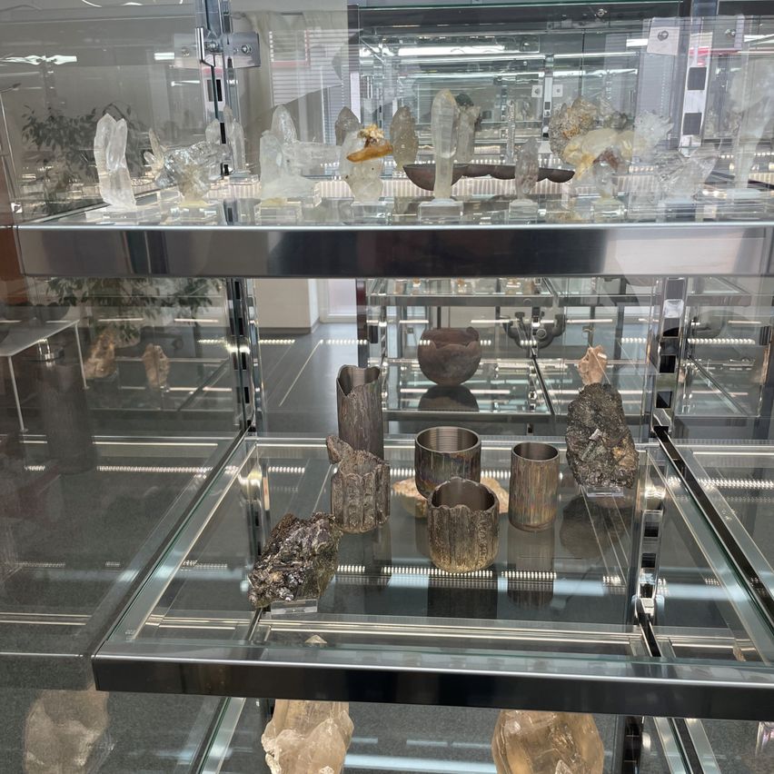 Eine Glasvitrine mit verschiedenen Kristallen, Mineralien und geschliffenen Steinen auf mehreren Glasregalen.