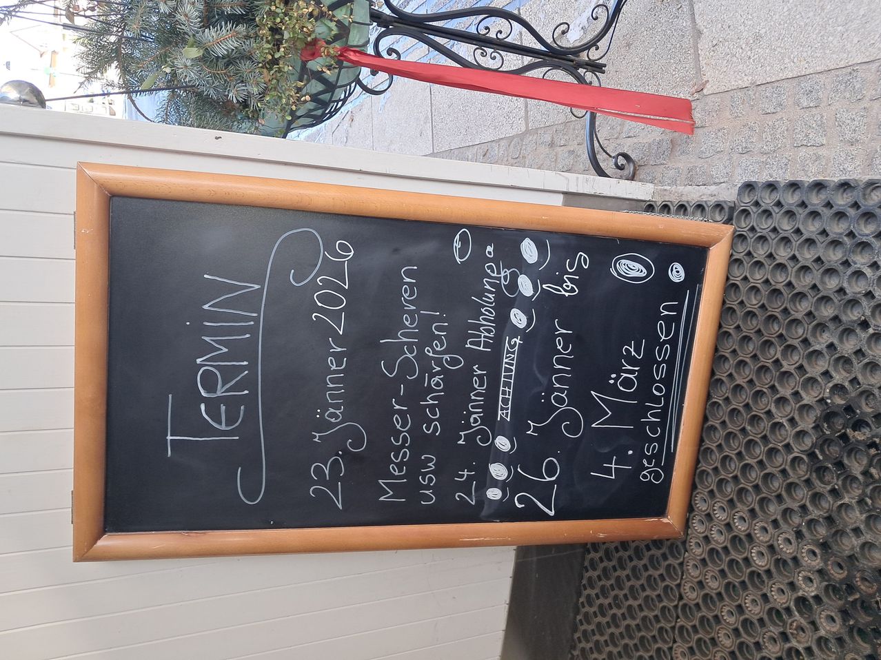 Ein Tafel zeigt einen handgeschriebenen Zeitplan für ein Restaurant oder Cafe. Es enthält Daten, Veranstaltungen und Speisen, wobei der oberste Eintrag 'TERMINI' lautet.