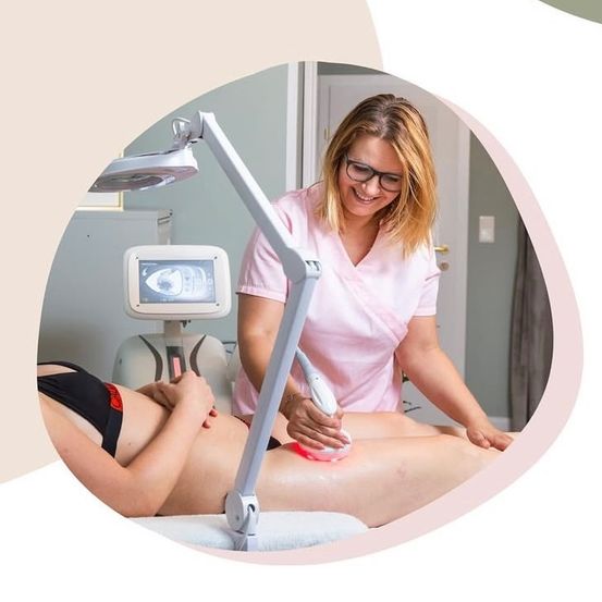 Eine Frau unterzieht sich einer Laserbehandlung zur Hautverjüngung. Sie liegt auf einem Tisch, während eine Technikerin den Laser auf ihren Bauch aufträgt.