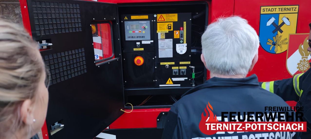 Ein Mann überprüft das Motorpanel eines Feuerwehrautos, mit verschiedenen Steuerelementen und Beschriftungen sichtbar.