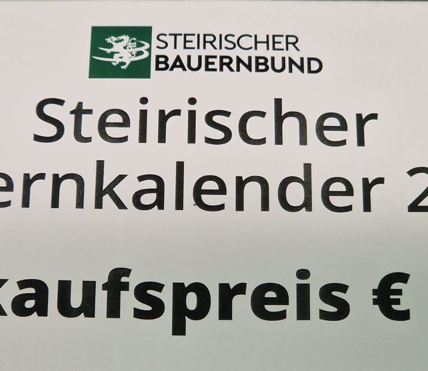 Ein weißer Schild mit einem Logo und dem Text 'Steirischer Bauernbund' über dem Titel 'Steirischer Kalender'. Darunter ist ein Preis in Euro angegeben.