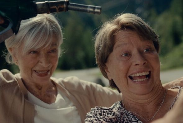 Zwei Frauen lächeln und posieren für ein Foto, während eine eine Zapfsäule hält.