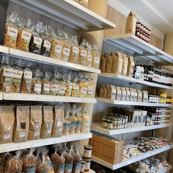 Ladeninneres mit verschiedenen Tüten mit Cerealien, Getreide, Nüssen und Trockenfrüchten auf Regalen, zusammen mit Gläsern und Flaschen von Produkten.